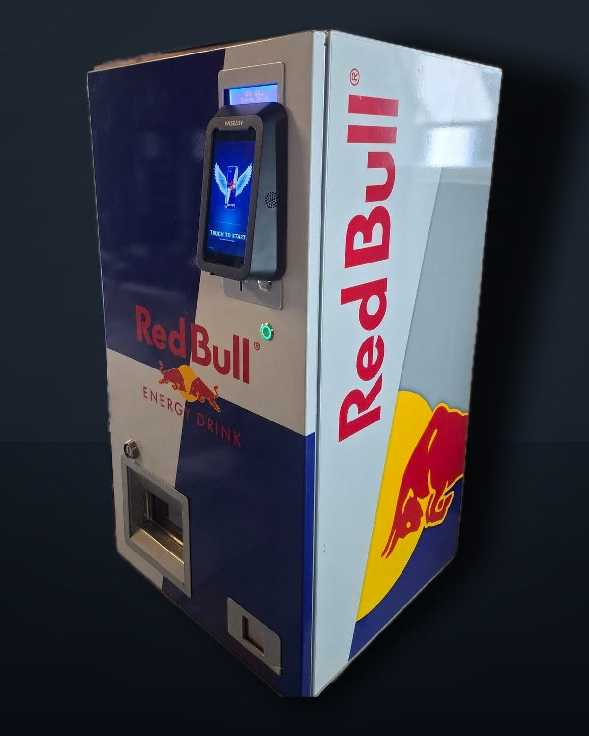 A Red Bull-branded vending machine with a VendBot P5L terminal fitted, seen from the side